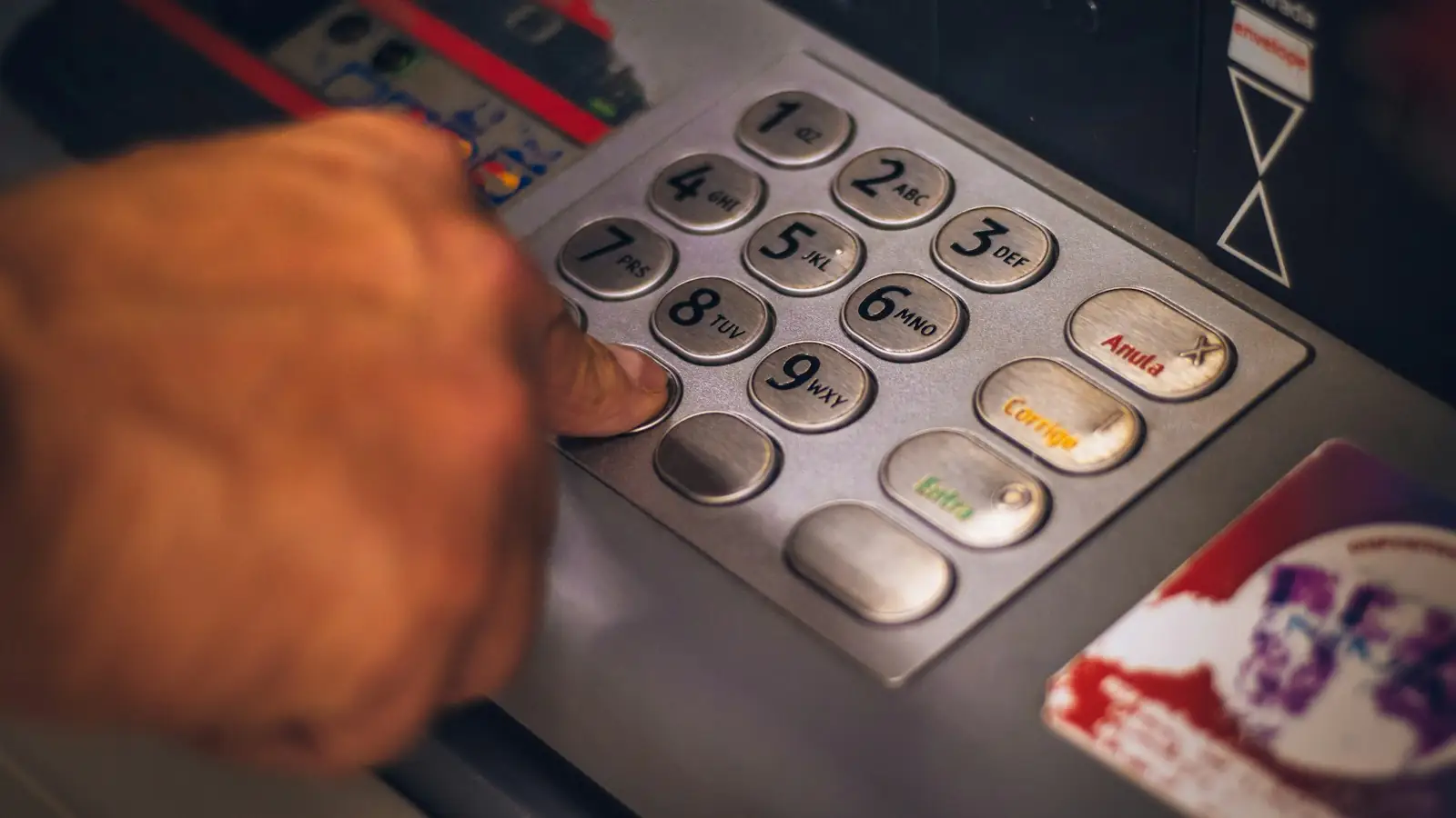 Hand entering a PIN at a bank ATM keypad