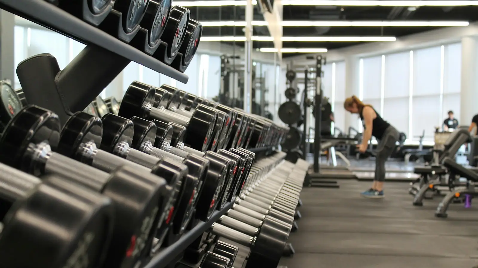 Gym with rows of dumbbells and people training