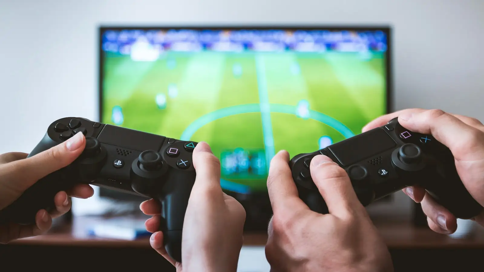 Two players holding game controllers in front of a football video game
