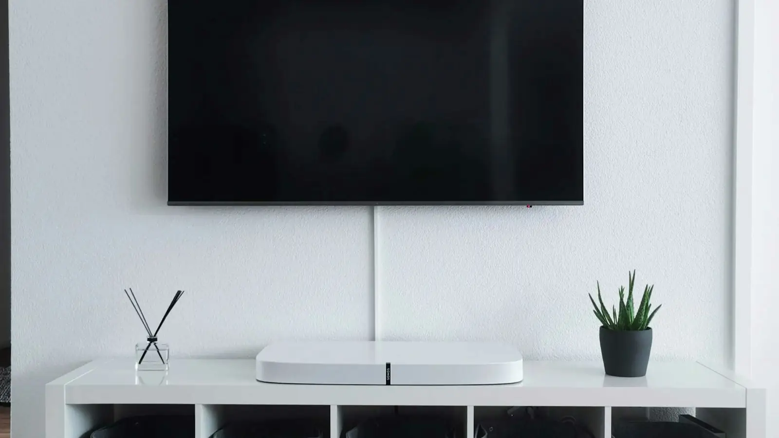 Wall-mounted television above a white media cabinet