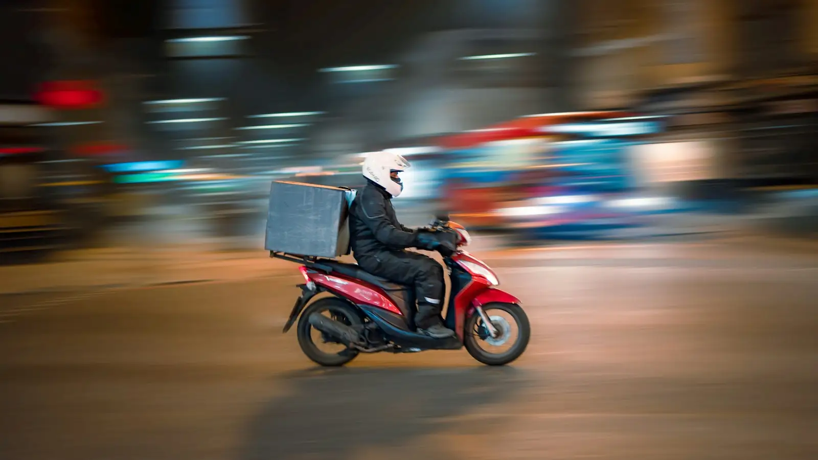 Delivery rider on a scooter with a delivery box at night