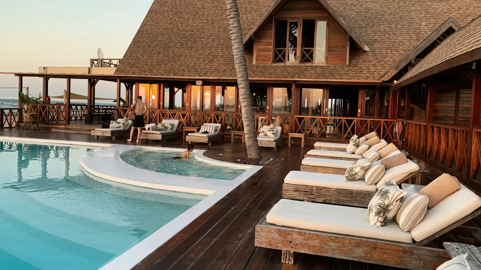 Resort pool with sun loungers beside a wooden lodge